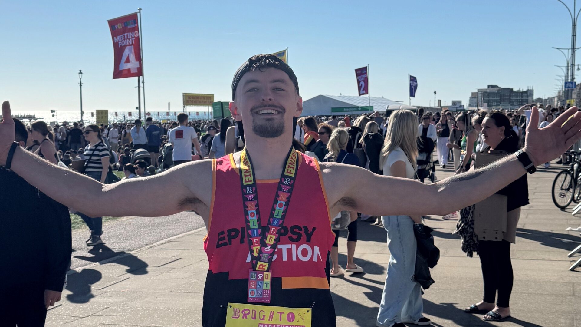 Epilepsy Action' runner finished Brighton Marathon 2025 at the seafront. Open up his arms and smiling happily.