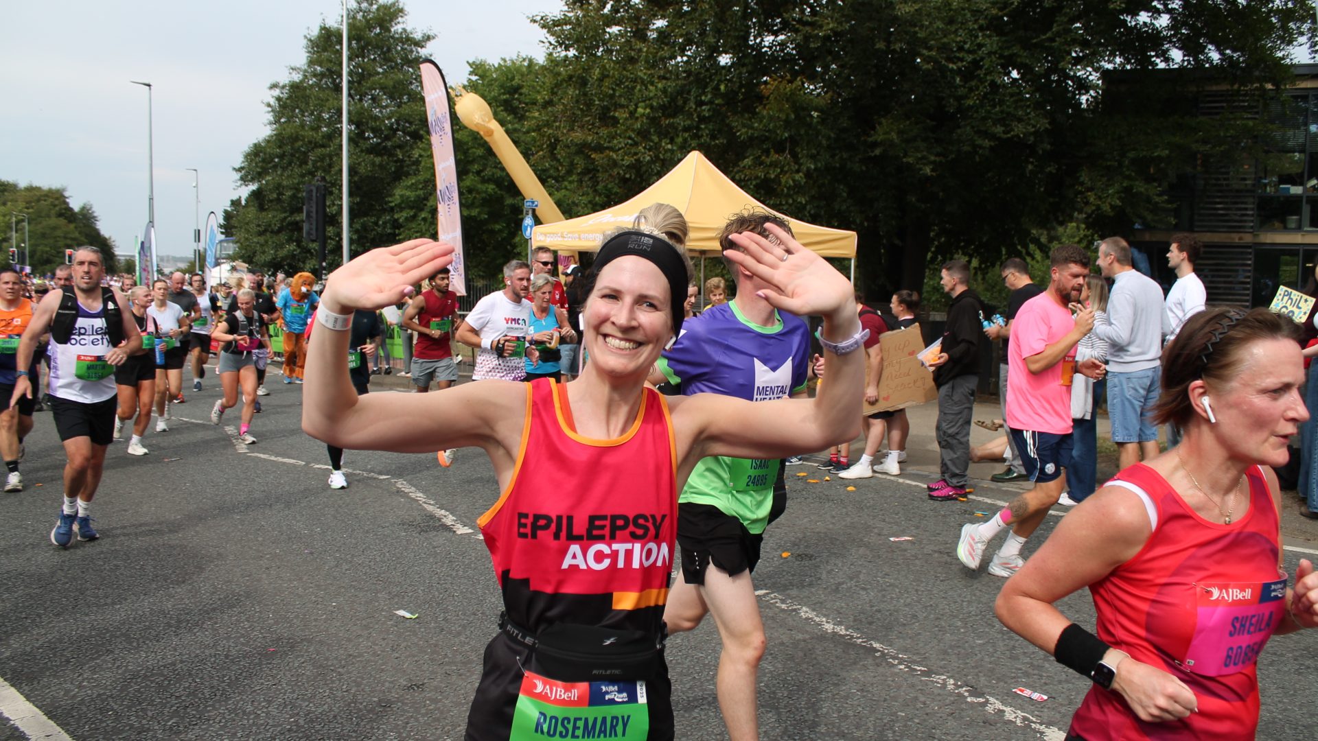 EA Runner passing through mile 4 waving her both hands up to our cheer team