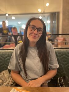 Rachel - a young woman with glasses and long brown hair sat at a restaurant