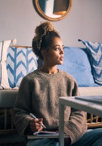 Young woman daydreaming in her living room while working
